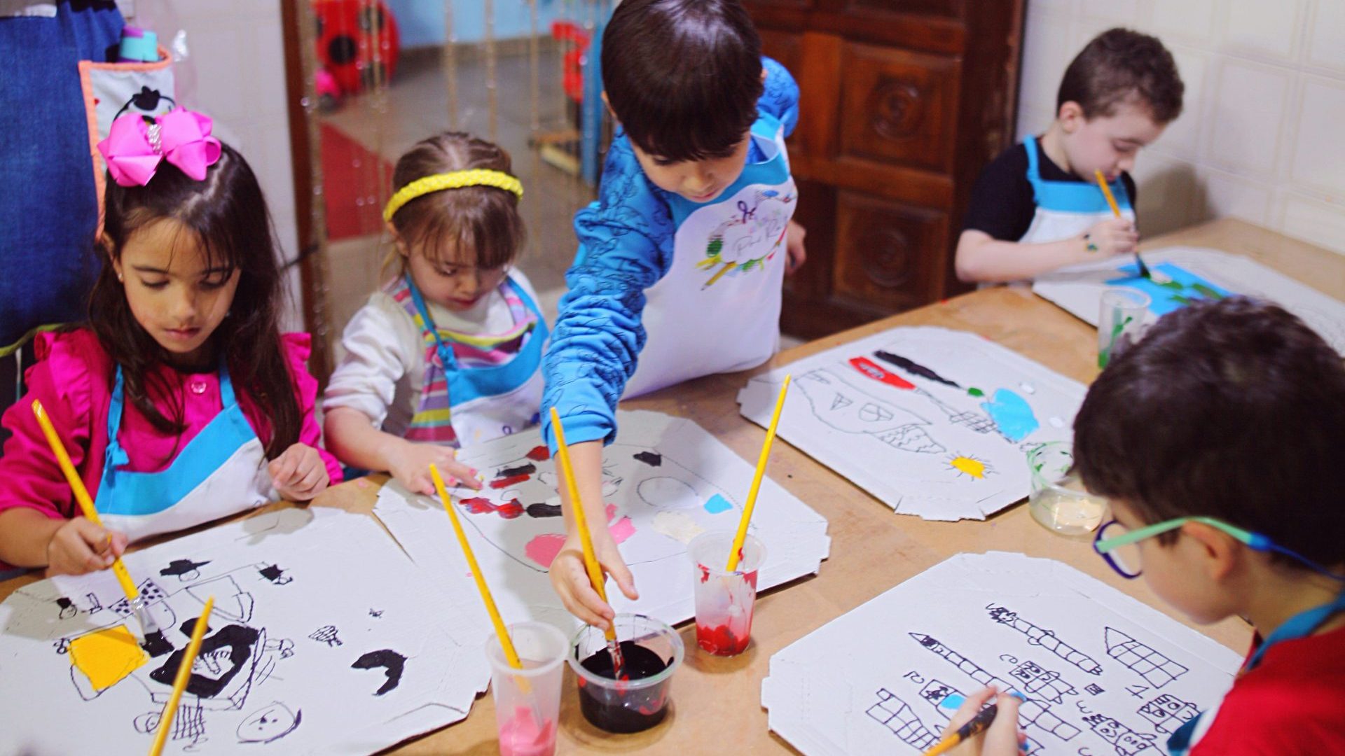 a group of children sitting at a table doing crafts